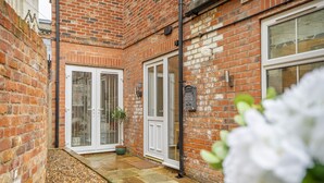 A brick building with a tiled patio, white doors, and a small garden area. - Micklegate Hideaway  -  Sleeps 4 Guests  in 2 Bedrooms (York)