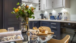 A modern kitchen with white cabinets, a coffee machine, and a vase with flowers on the counter. - Micklegate Hideaway  -  Sleeps 4 Guests  in 2 Bedrooms (York)