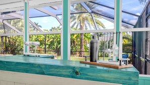 Ein Poolbereich mit Holzterrasse, Liegestuhl und Ventilator.