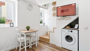 Un espacio habitable compacto con comedor, lavadora y televisor montado en la pared.