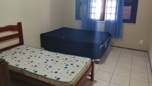 A room with a bed, a small table, a window with curtains, and a radiator.