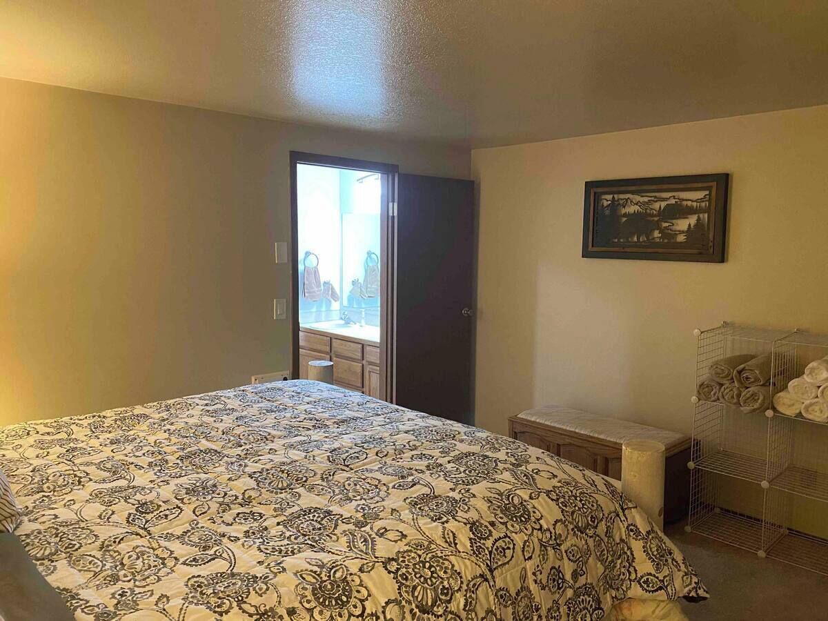 A bedroom with a bed, a bench, a radiator, and a window with a view.