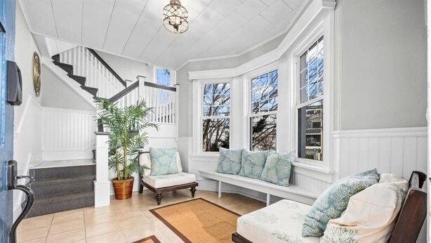 A spacious living room with a staircase, a large window with a view, and a cozy seating area. - 6BR Beach Block Paradise - Ocean Views - Sleeps 20 (Ventnor City)