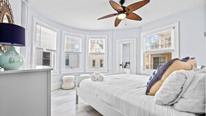 A bedroom with a bed, a ceiling fan, a window, and a nightstand. - 6BR Beach Block Paradise - Ocean Views - Sleeps 20 (Ventnor City)