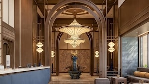 Un hall d’entrée avec un comptoir de réception, un plafond en arc de cercle, des lampes suspendues et un espace salon.