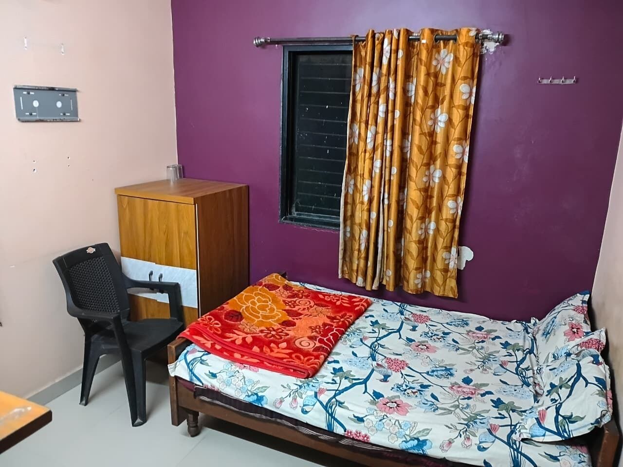 A bedroom with a bed, a desk, a chair, a wardrobe, and a window with curtains.