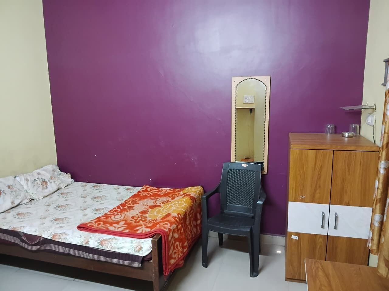 Une pièce comprenant un lit, une chaise, une armoire et un miroir.