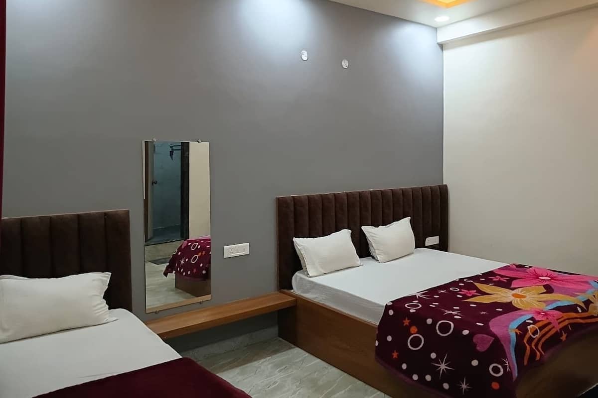 A hotel room with two beds, a large mirror, and a ceiling light.