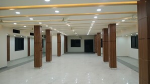 A spacious hotel corridor with marble floors, wooden pillars, and recessed lighting. - Hotel Keshav (Savner)