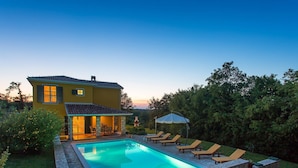 Une maison avec une piscine, un espace extérieur aménagé et un jardin.