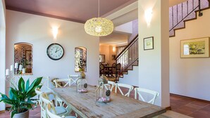 Un coin repas avec une table en bois, des chaises blanches, une plante en pot et des objets décoratifs.