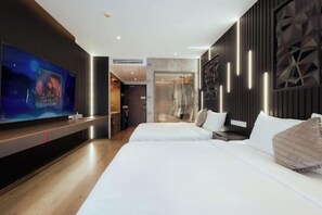 A modern hotel room with a large flat-screen TV, a bed with white linens, and a wooden floor. - Couple & Co. Boutique Mandala (Phan Thiet)