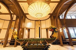 A traditional boat-shaped bench in a lobby with a large fan light above. - Couple & Co. Boutique Mandala (Phan Thiet)