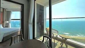 A bedroom with a large window, a bed, a chair, and a small table. - Couple & Co. Boutique Mandala (Phan Thiet)