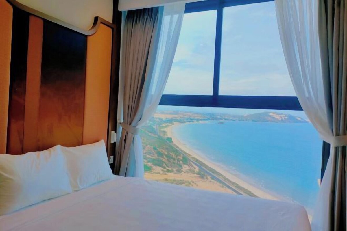 A hotel room with a large window, a bed, and curtains.