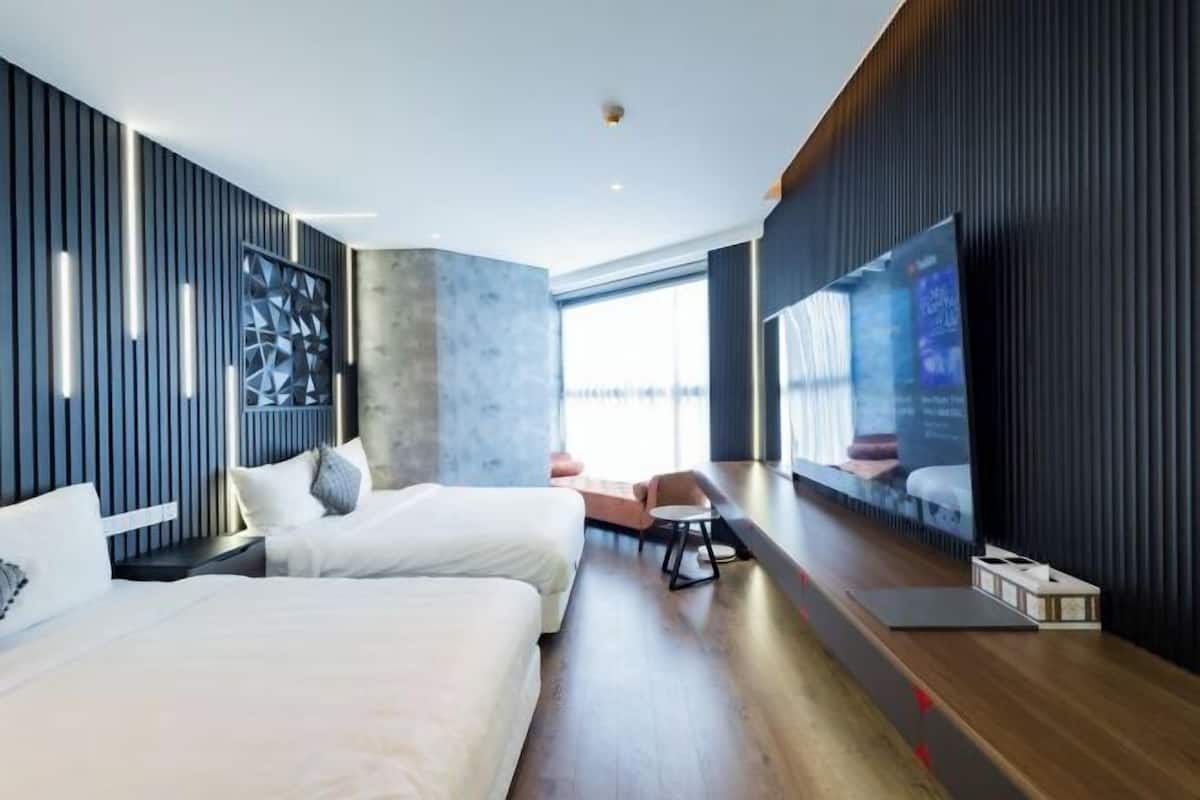 Una habitación de hotel moderna con dos camas, un televisor y un ventanal grande.