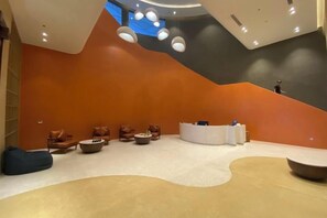 A modern lobby with a curved seating area, a reception desk, and a staircase. - Couple & Co. Boutique Mandala (Phan Thiet)