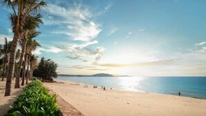 A beach with palm trees, a sandy shore, and a clear sky. - Couple & Co. Boutique Mandala (Phan Thiet)
