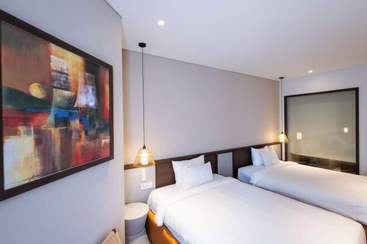 Una habitación de hotel moderna con dos camas individuales, un cuadro abstracto grande en la pared y un ventanal con vistas.