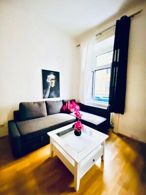 A modern living room with a grey sofa, a white coffee table, and a black and white poster on the wall. - 2BR Apartment Close to Stadthalle (Vienna)