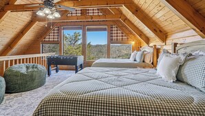 A cozy attic bedroom with a checkered bed, a ceiling fan, and a foosball table. - Cozy Log Cabin - Hot Tub, Games, & Mountain Views (Sevierville)