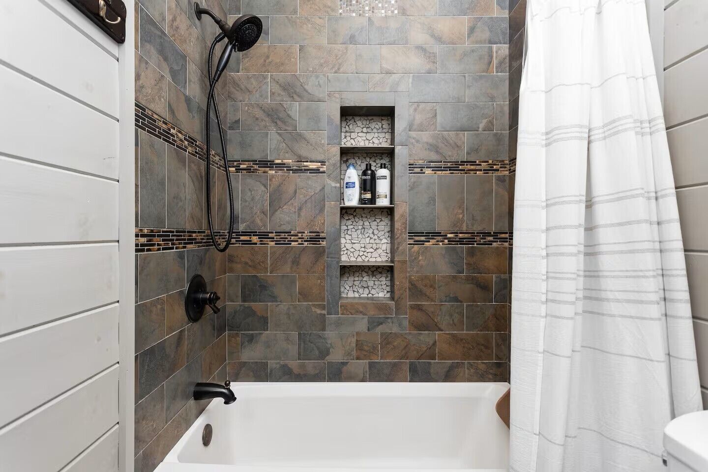 Une salle de bain avec une baignoire, une douche et des murs carrelés.