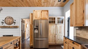 Una cocina con armarios de madera, un refrigerador de acero inoxidable y una encimera de madera.