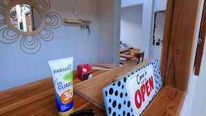 Ein Zimmer mit Holztisch, Spiegel, einem Schild, das anzeigt, dass der Raum geöffnet ist, und einer Sonnencremetube.