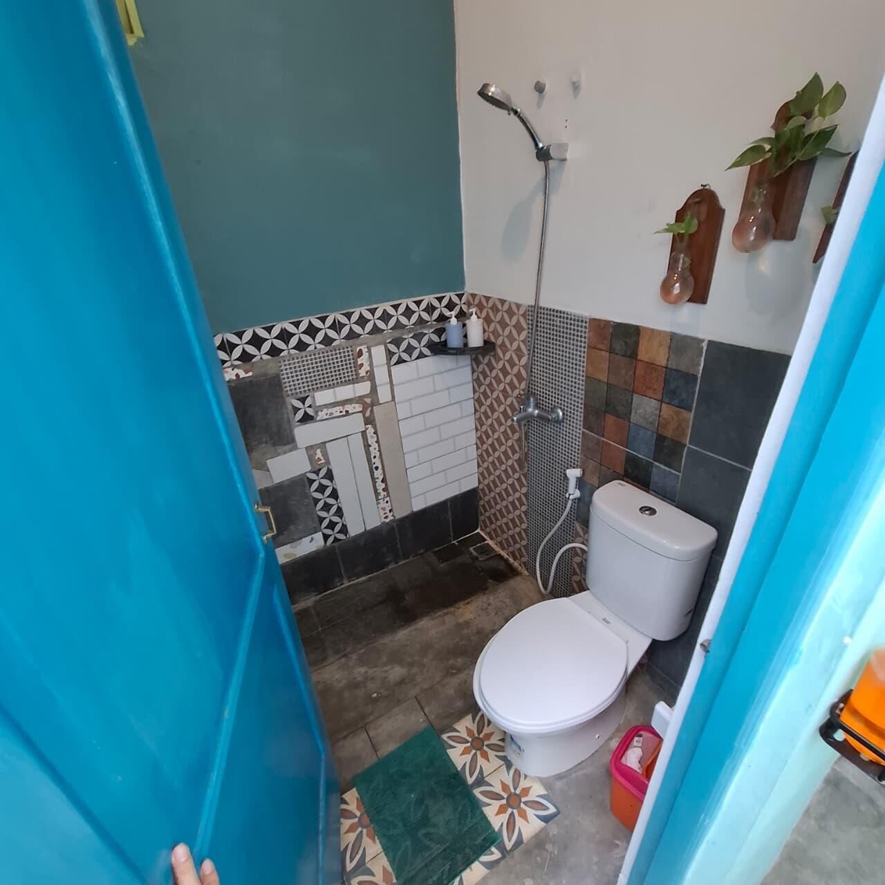 A bathroom with a white toilet, a shower, and a tiled wall with a geometric pattern.