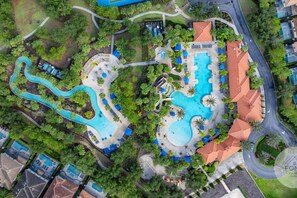 Eine Vogelperspektive eines Resorts mit mehreren Schwimmbecken, üppiger Bepflanzung und einer Mischung aus Wohn- und Geschäftsgebäuden.