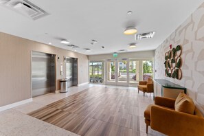 A spacious lobby with a wooden floor, a reception desk, and a seating area with chairs.