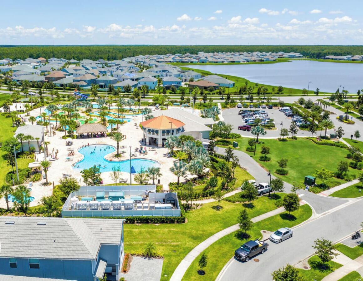 Et resort med flere swimmingpools, en stor bygning med et cirkulært tag, og en parkeringsplads.