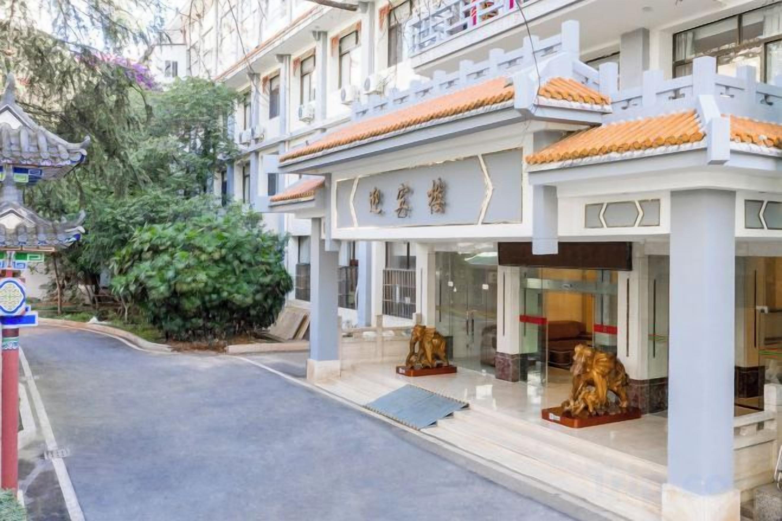 A hotel with a traditional architectural style, featuring a tiled roof and a prominent entrance with a statue.