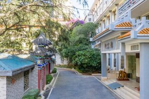 Une rue étroite bordée de bâtiments à l’architecture traditionnelle, notamment un édifice de style pagode et un bâtiment moderne doté d’un toit en tuiles.