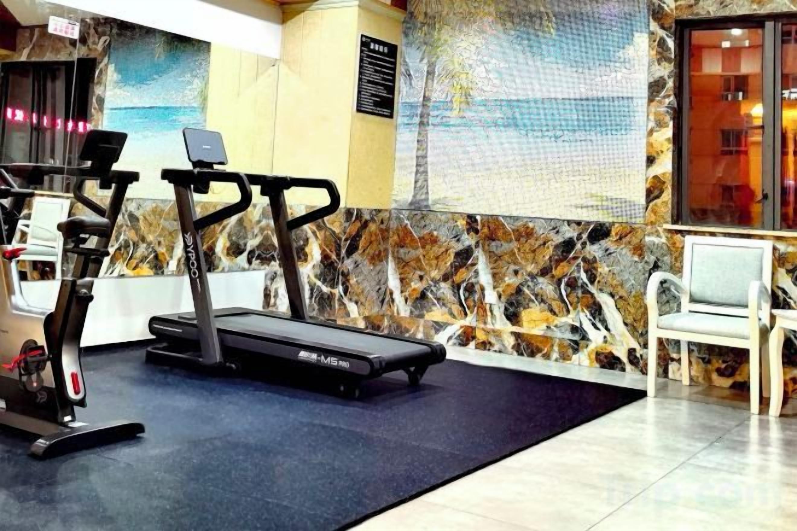A gym with exercise equipment, a seating area, and a decorative wall.