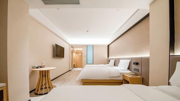A hotel room with a large bed, a bedside table, a TV mounted on the wall, and a small round table with a chair. - Kunming Southwest Hotel Yingbin Building (Kunhua Hospital) (Kunming)