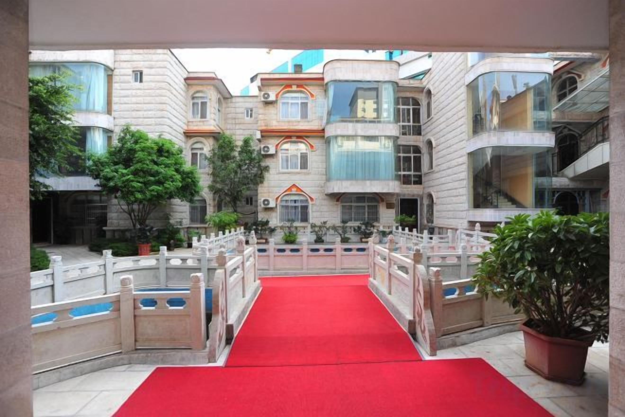A red carpet leading to a building with multiple balconies and a central courtyard.