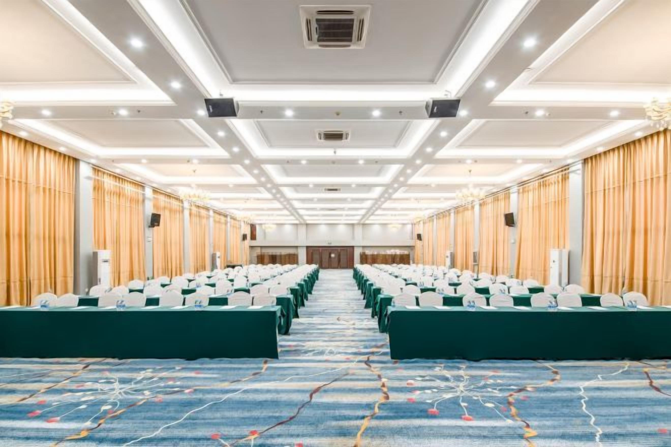 A conference room with rows of chairs, a carpeted floor, and a ceiling with recessed lighting.