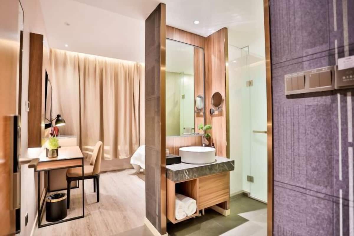 A modern bathroom with a vanity, mirror, and shower area.