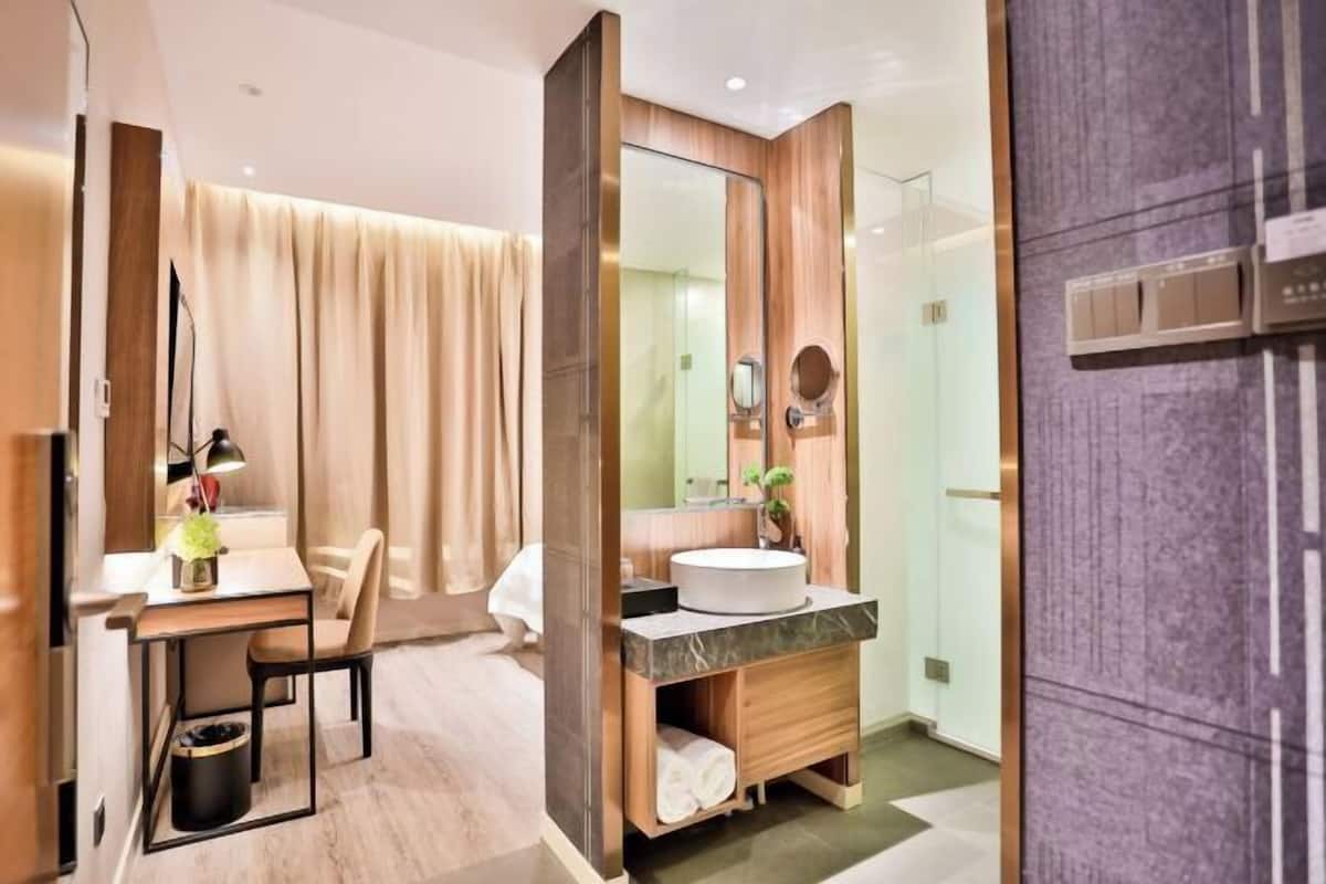 A modern bathroom with a vanity, mirror, and a shower area.