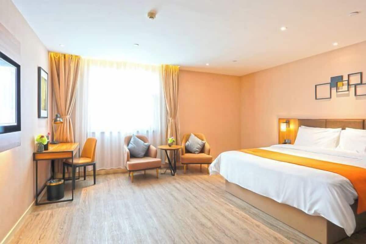 A hotel room with a bed, two armchairs, a desk, and a small table.