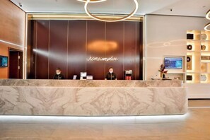 A reception desk with a marble top and a dark wooden backdrop. - Homeinn Plus Hotel (Qingdao Licun Subway Station Pedestrian Street) (Qingdao)