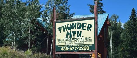A sign for Thunder MTN Motorsports, Inc. with contact information and services listed.