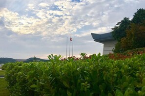 A building with a flagpole and a flag, surrounded by greenery.