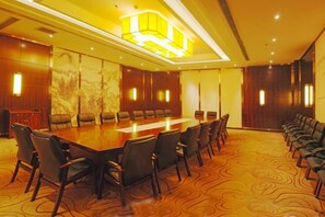 A conference room with a long table, multiple chairs, and a carpeted floor. - Xiaolangdi Zhongzhou International Hotel (Jiyuan)