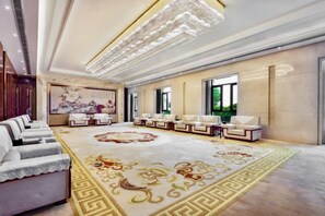 Un espacioso vestíbulo de hotel con una imponente araña, un cuadro grande con motivos florales y una alfombra estampada.