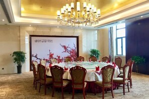 A conference room with a round table, chairs, a chandelier, and a projection screen. - Xiaolangdi Zhongzhou International Hotel (Jiyuan)