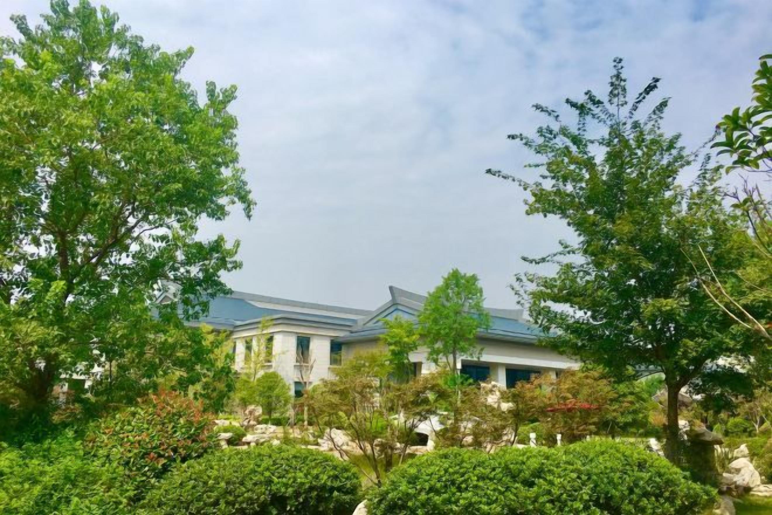 A building with a modern architectural style, surrounded by lush greenery and trees.