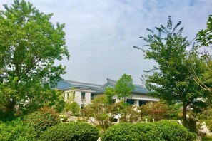 A building with a modern architectural style, surrounded by lush greenery and trees. - Xiaolangdi Zhongzhou International Hotel (Jiyuan)