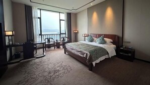 Una habitación de hotel con una cama grande, un escritorio, una silla, un televisor y vista al mar.